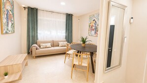 A living room with a sofa, a dining table with chairs, a small wooden bench, and a potted plant. - Centrally located apartment for 6,Tarifa (TARIFA)