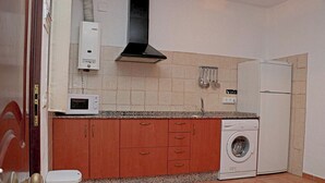 A compact kitchen with a microwave, stove, sink, and washing machine. - Bungalow in complex with shared pool (CONIL DE LA FRONTERA)