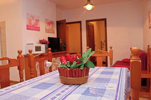Enjoy meals with family and friends in this cozy dining area, featuring a table for four, a wicker basket with fresh flowers, and comfortable chairs.