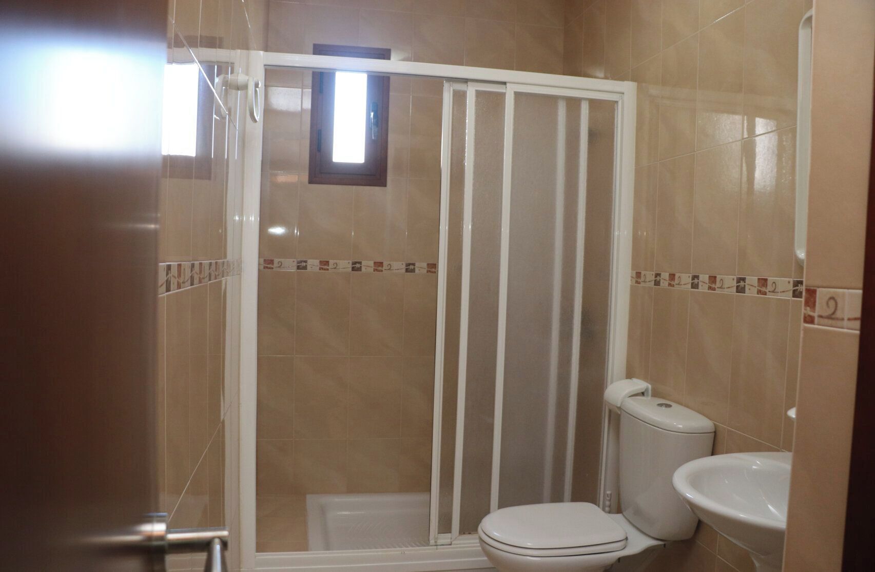 A bathroom with a shower enclosure, toilet, and sink.