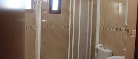 A bathroom with a shower enclosure, toilet, and sink.