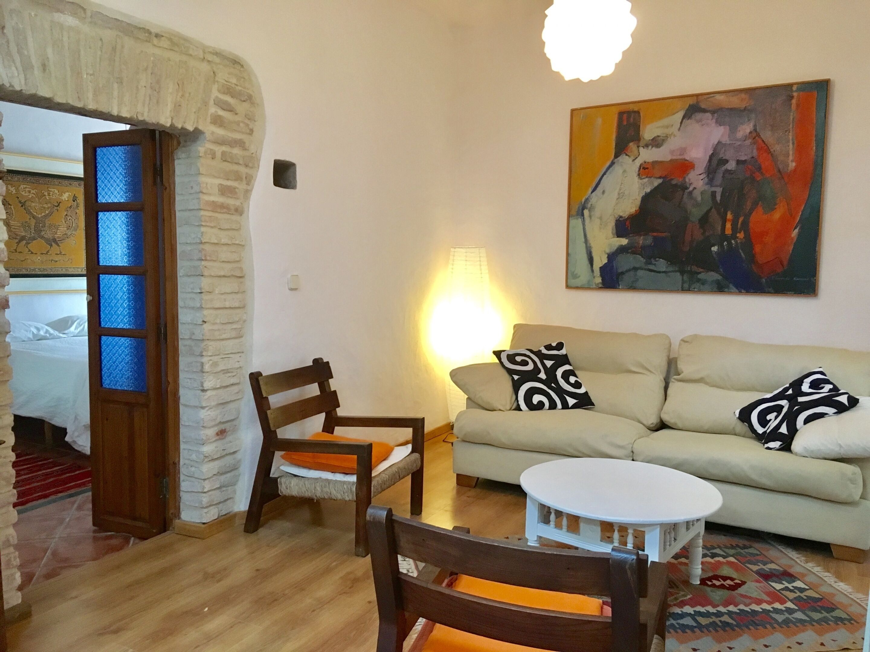 A living room with a sofa, two chairs, a small table, and a painting on the wall.