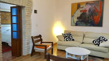 A living room with a sofa, two chairs, a small table, and a painting on the wall.