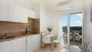 A modern kitchen with white cabinets, a wooden backsplash, a dining area with a table and chairs, and a balcony with a view of the landscape. - Apartment Arausa with Pool III (Vodice)