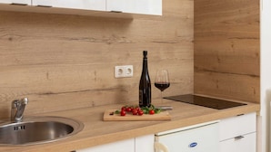 A kitchen with a wooden countertop, a stainless steel sink, a wine bottle, and a glass of red wine. - Apartment Arausa with Pool III (Vodice)