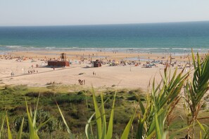 Una playa con una torre de salvavidas, sombrillas y gente.