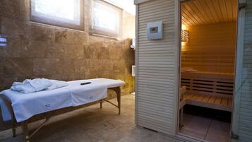 Experience relaxation in this serene spa room featuring a massage table, sauna bench, and temperature control.