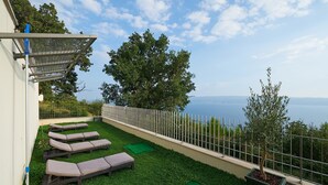 A balcony with a view of the sea, equipped with lounge chairs and a pergola. - Luxury Villa Venera with Pool (Jesenice)