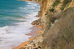 Une plage côtière bordée de falaises rocheuses et d’un rivage sablonneux.