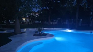 Ein Schwimmbecken mit gewölbter Kante und einer kleinen Palme in der Mitte.