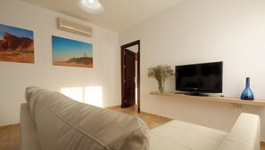 Una sala de estar con un sofá, un televisor y un jarrón con flores.