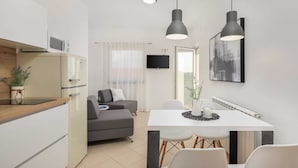 A modern kitchen with a built-in oven, a dining area with a white table and chairs, and a gray sofa. - Apartment Arausa with Pool IV (Vodice)