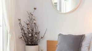 A bedroom with a bed, a round mirror, a potted plant, and a window with curtains. - Apartment Arausa with Pool IV (Vodice)