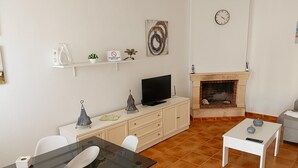 A living room with a fireplace, a television, a glass table, and a white sofa. - Villa Mari Carmen, with pool and BBQ (chiclana de la frontera)