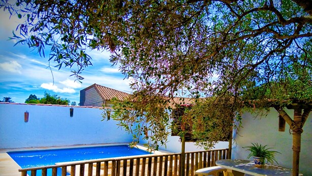 A swimming pool surrounded by a wooden fence, with a table and benches nearby. - Villa Mari Carmen, with pool and BBQ (chiclana de la frontera)