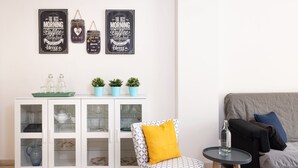 A room with a white cabinet with glass doors, a patterned armchair with a yellow cushion, and a small round table with a glass bottle. - Apartment with free parking in Marbella (Marbella)