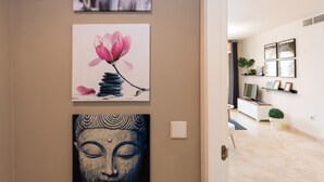 A hallway with artwork on the wall, a white console table, a potted plant, and a television. - Apartment with free parking in Marbella (Marbella)