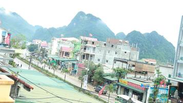 Vista de la calle con edificios, una estructura de techo verde y montañas al fondo.