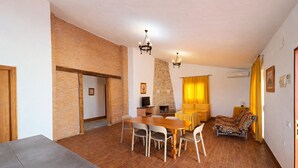 Una habitación con una mesa de comedor, sillas, un sofá, un televisor y una chimenea.