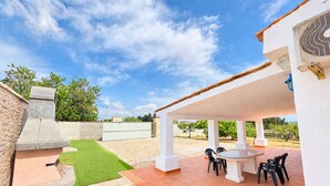 Un patio con una parrilla, mobiliario exterior y una zona cubierta.