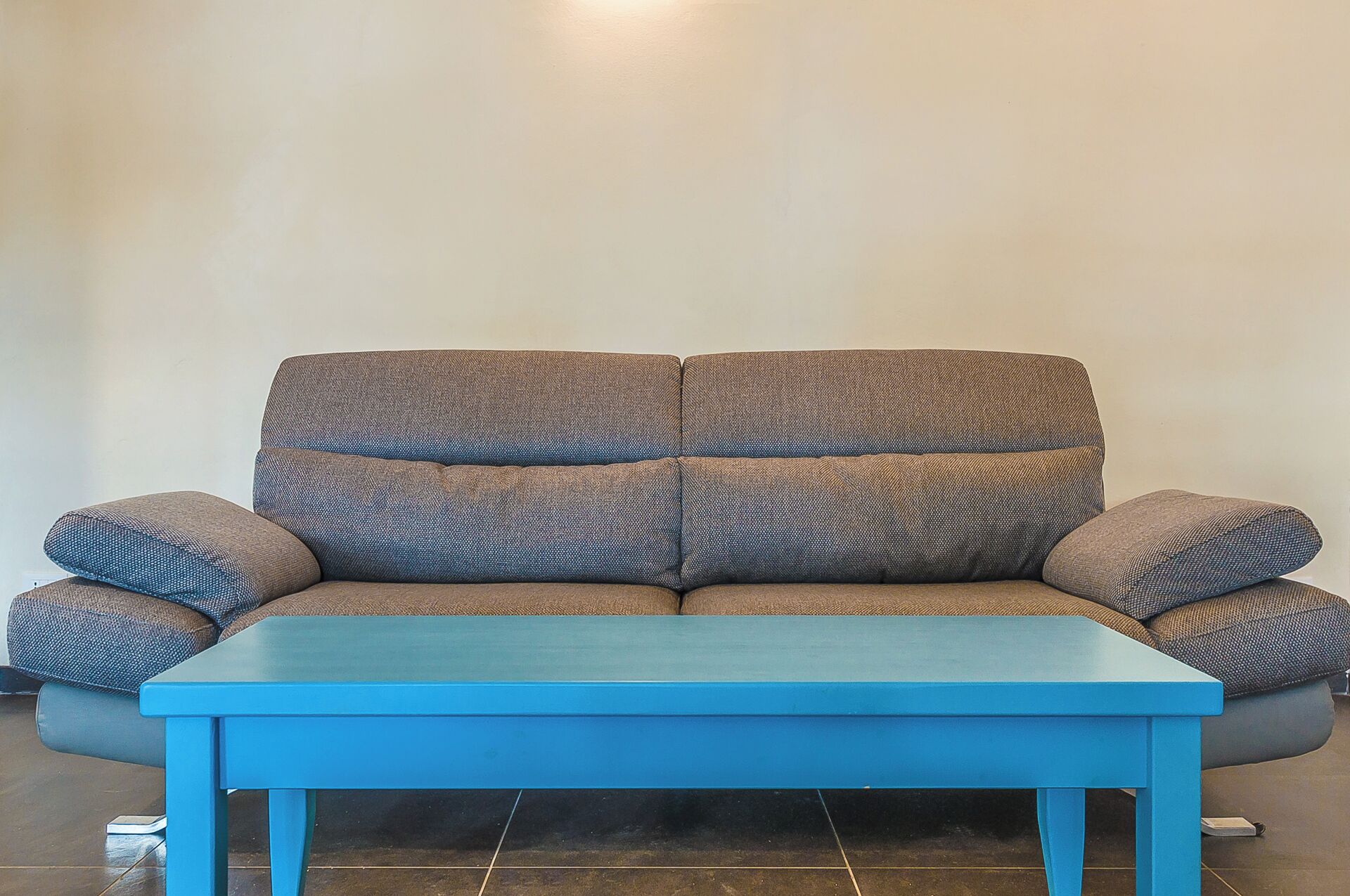 Un sofá con una mesa azul frente a él.