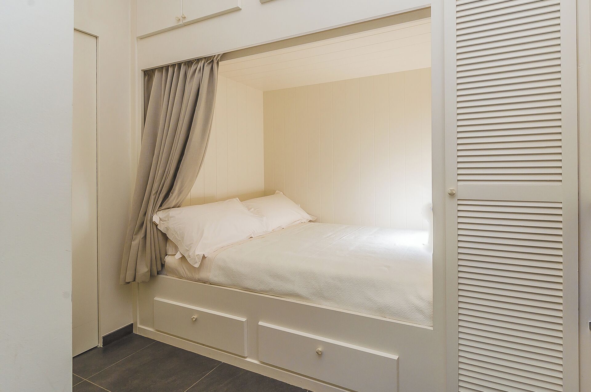 Een slaapkamer met een bed, gordijnen en een kledingkast.