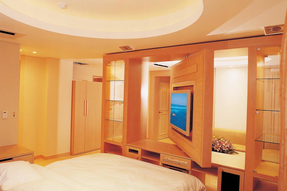 A hotel room with a bed, a TV, and built-in wooden cabinets.