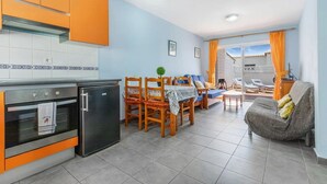 A compact kitchen with orange cabinets, a refrigerator, and a dining area with a table and chairs. - Great location, apartment Fuerteventura (Costa Calma (Fuerteventura))