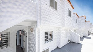 A white building with multiple windows and a door, featuring a textured facade and a tiled roof. - Great location, apartment Fuerteventura (Costa Calma (Fuerteventura))