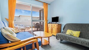A room with a balcony, a sofa, a table, and a TV. - Great location, apartment Fuerteventura (Costa Calma (Fuerteventura))