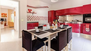 A modern kitchen with red cabinets, a dining table with black chairs, and a kitchen island.