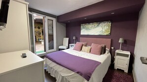 A bedroom with a bed, a nightstand, a dresser, and a painting on the wall.