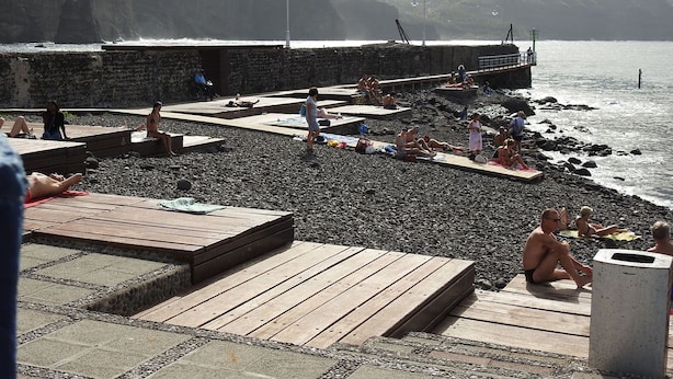 A rocky beach with wooden platforms and a pier extending into the water.