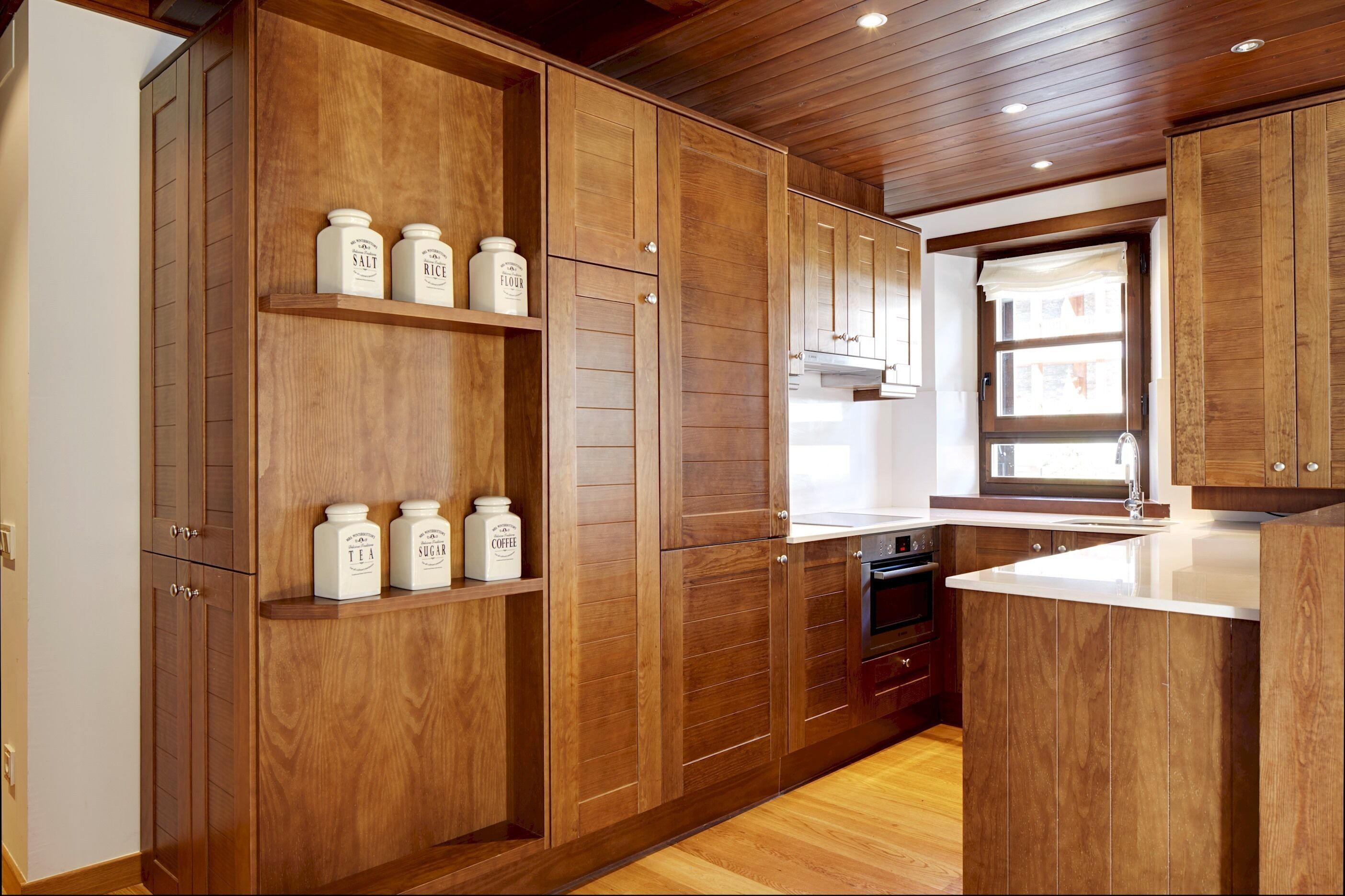 A kitchen with wooden cabinets, a built-in oven, and a window.