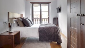 A bedroom with a bed, a nightstand, a lamp, a TV, and a wardrobe. - Val de Ruda Luxe 21 by FeelFree Rentals (Baqueira)