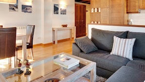 A cozy living room with a grey sofa, a glass coffee table, and a dining area with a white table and chairs. - Val de Ruda Luxe 21 by FeelFree Rentals (Baqueira)