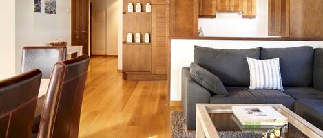 Uma sala de estar moderna com um sofá cinza, armários de madeira e uma mesa de centro com objetos decorativos.