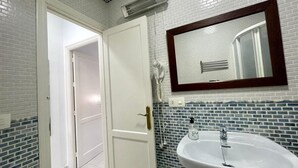 Ein Badezimmer mit einer weißen Tür, einem weißen Waschbecken und einem Spiegel darüber sowie einer blauen Fliesenwand.