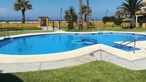 Una piscina con agua cristalina azul, rodeada de palmeras y una valla.
