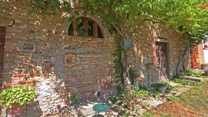 Ein rustikales Steinhaus mit einer mit Efeu bewachsenen Mauer, einem kleinen Rundbogenfenster und einer Tür.