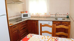 A compact kitchen with a microwave, sink, and wooden cabinets. - Two bedroom apartment in the centre (CONIL DE LA FRONTERA)