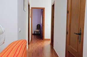 A narrow hallway with wooden flooring, a chair in the distance, and a door on the right. - Two bedroom apartment in the centre (CONIL DE LA FRONTERA)