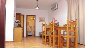 A dining area with a wooden table and chairs, a small cabinet, and a ceiling light.