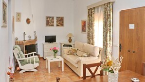 A living room with a sofa, armchair, television, and decorative items. - 4 person holiday villa with private pool (CONIL DE LA FRONTERA)