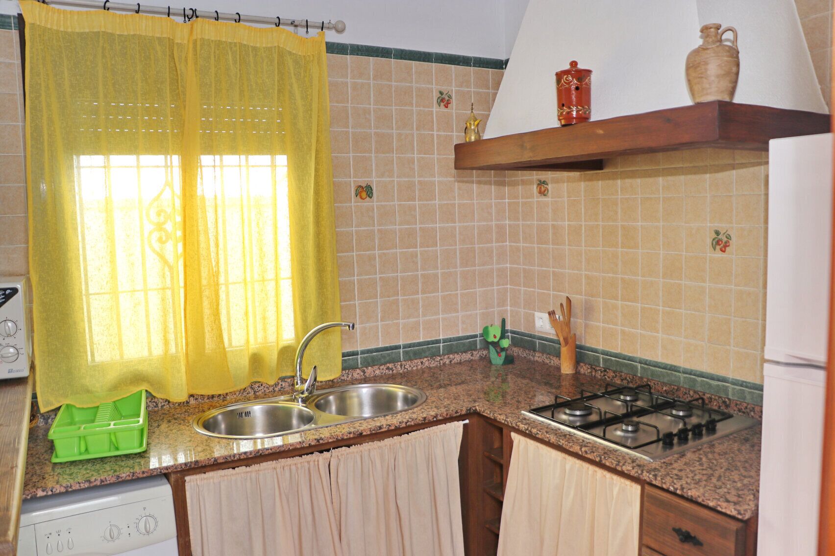 A kitchen with a gas stove, stainless steel sink, and a green dish rack.