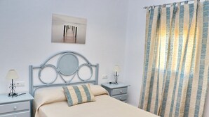 A neatly arranged bedroom with a bed, two bedside tables with lamps, a wall-mounted artwork, and patterned curtains. - 4 person holiday villa with private pool (CONIL DE LA FRONTERA)