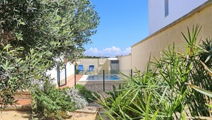 A courtyard with a swimming pool, surrounded by plants and a white building. - 4 person holiday villa with private pool (CONIL DE LA FRONTERA)