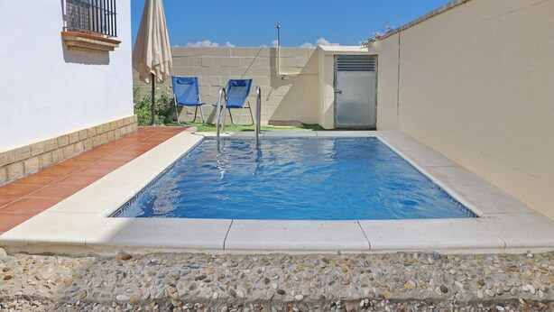 A rectangular swimming pool with two blue lounge chairs and a beige umbrella. - 4 person holiday villa with private pool (CONIL DE LA FRONTERA)
