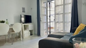 Un salon moderne comprenant un canapé, un téléviseur, un bureau et un coin repas.