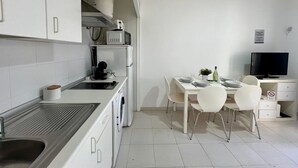 Une cuisine moderne avec des armoires blanches, un four à micro-ondes encastré et un coin repas comprenant une table et des chaises.